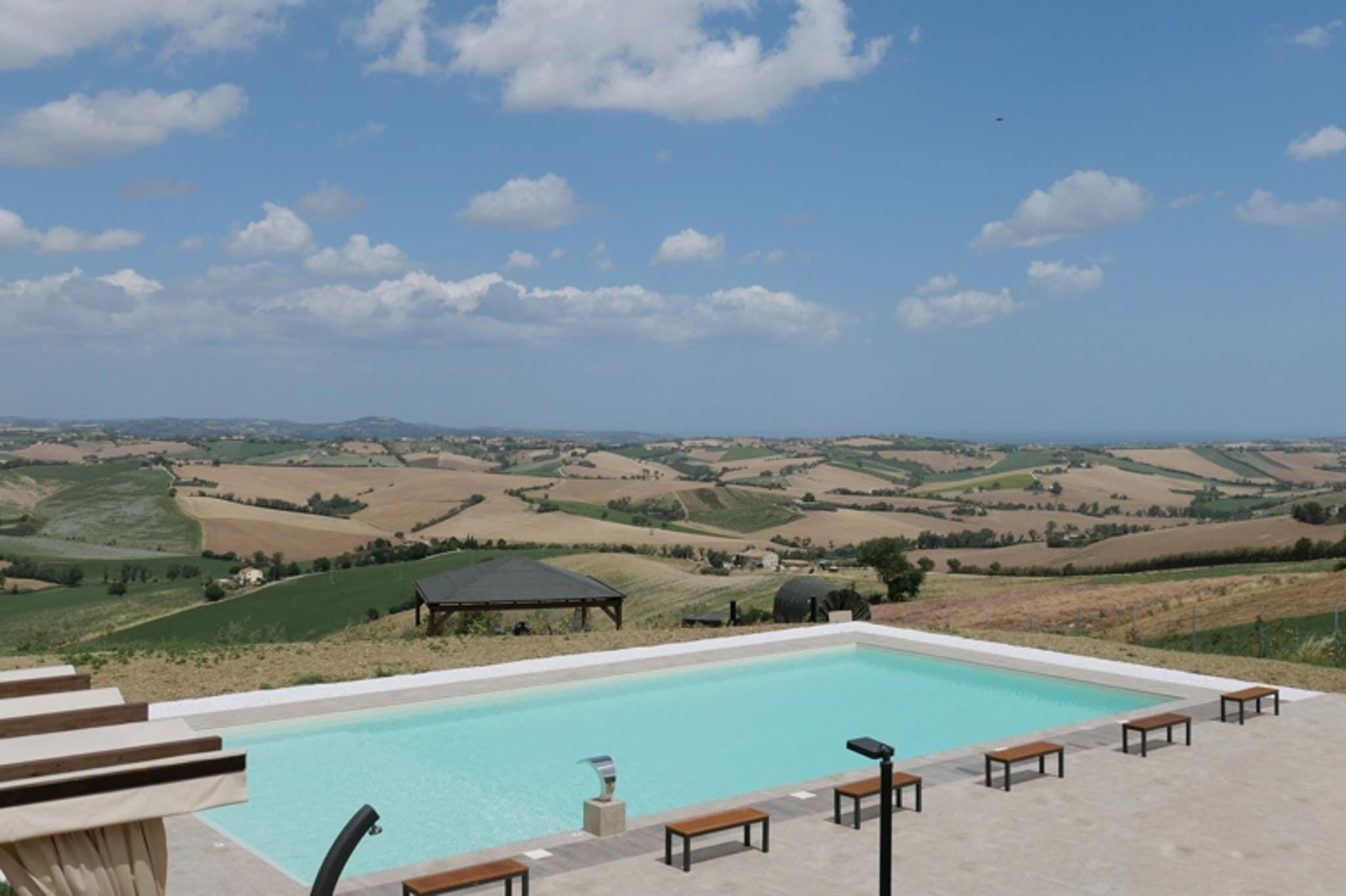 Une piscine avec vue sur des collines verdoyantes et un belvédère.