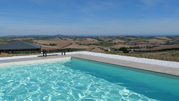 Una piscina con acqua cristallina e vista su dolci colline sullo sfondo.
