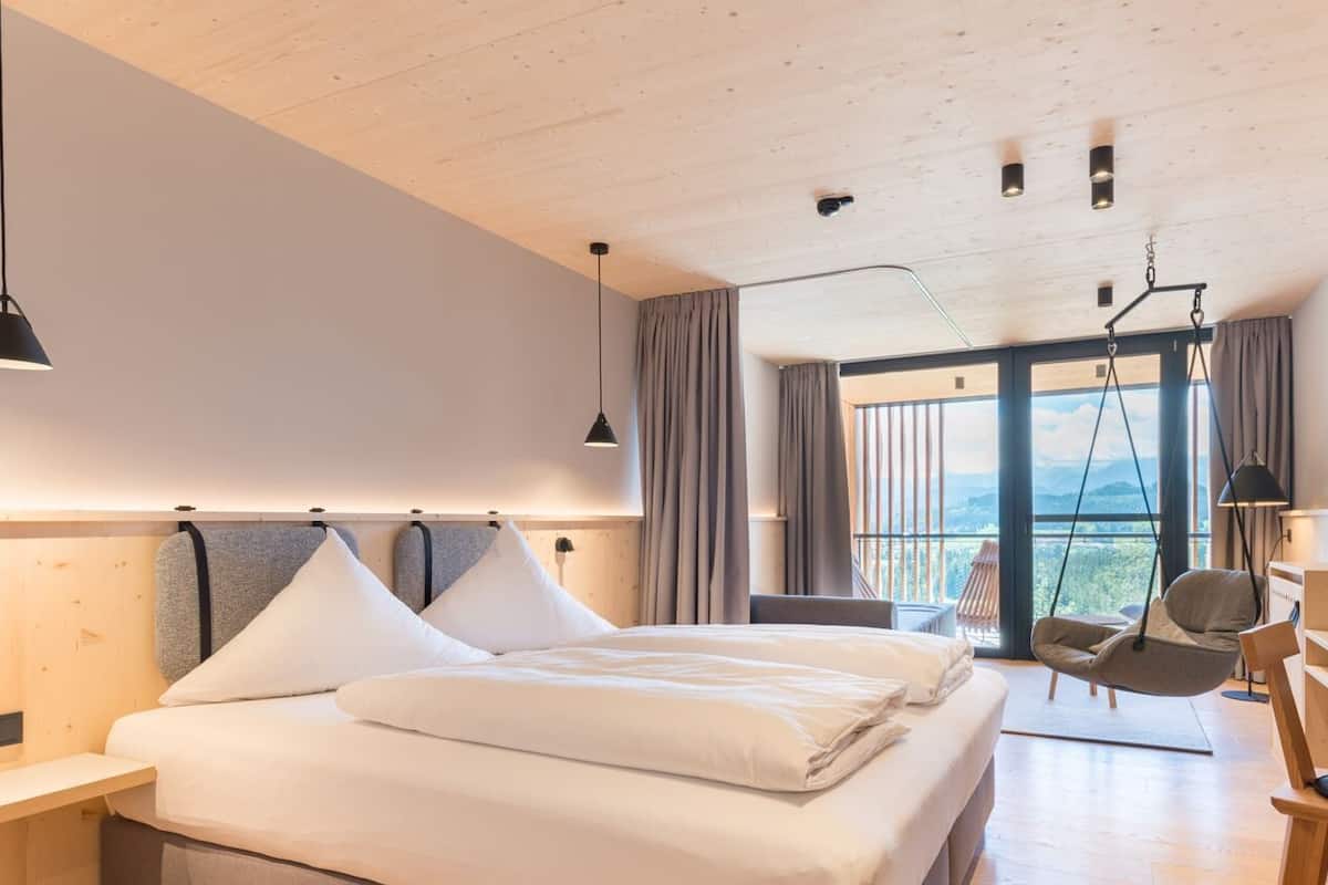 Een moderne slaapkamer met een groot bed, een hangstoel en een bureau.