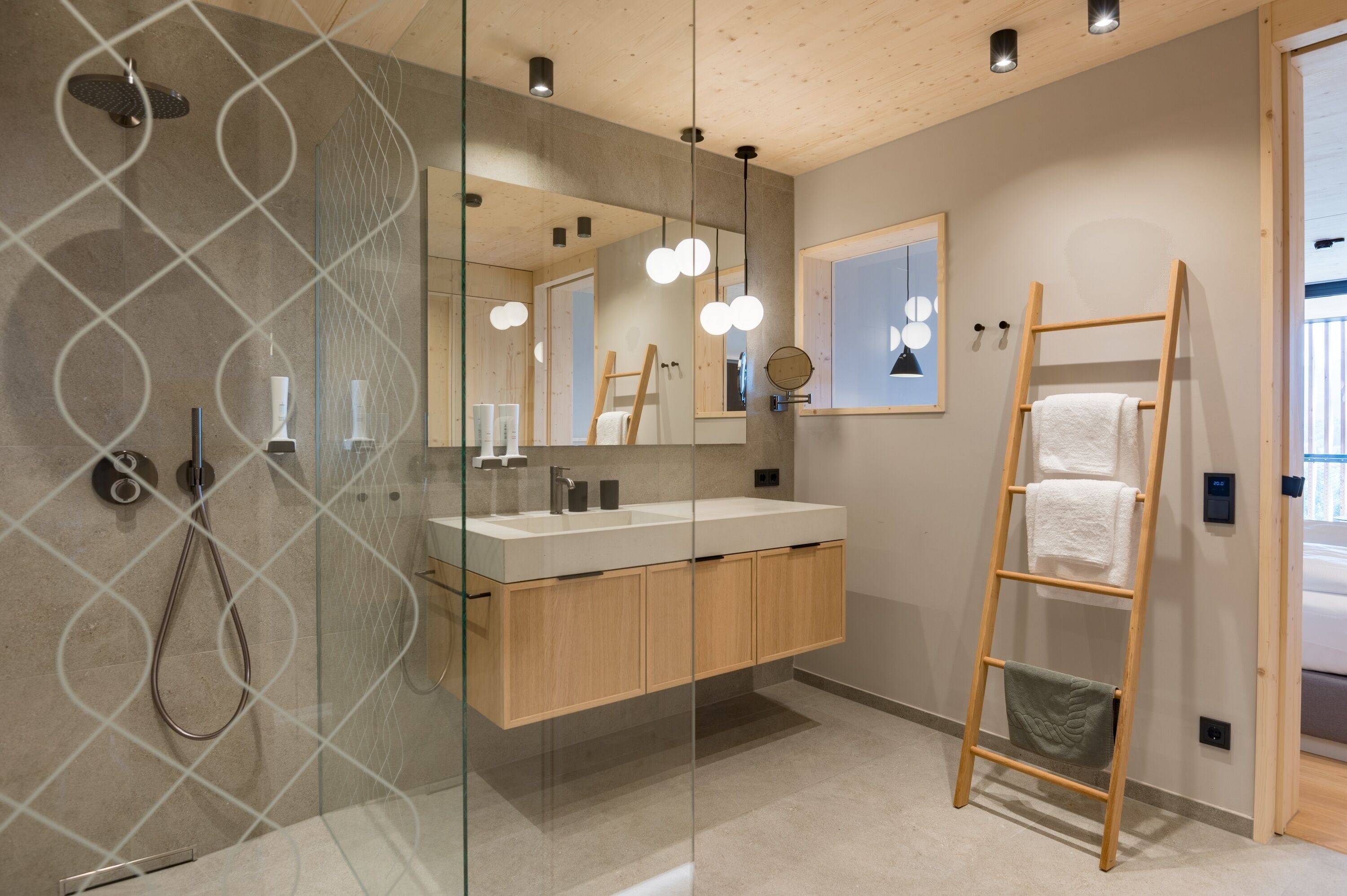 A modern bathroom with a glass shower enclosure, wooden vanity, and a wooden ladder.
