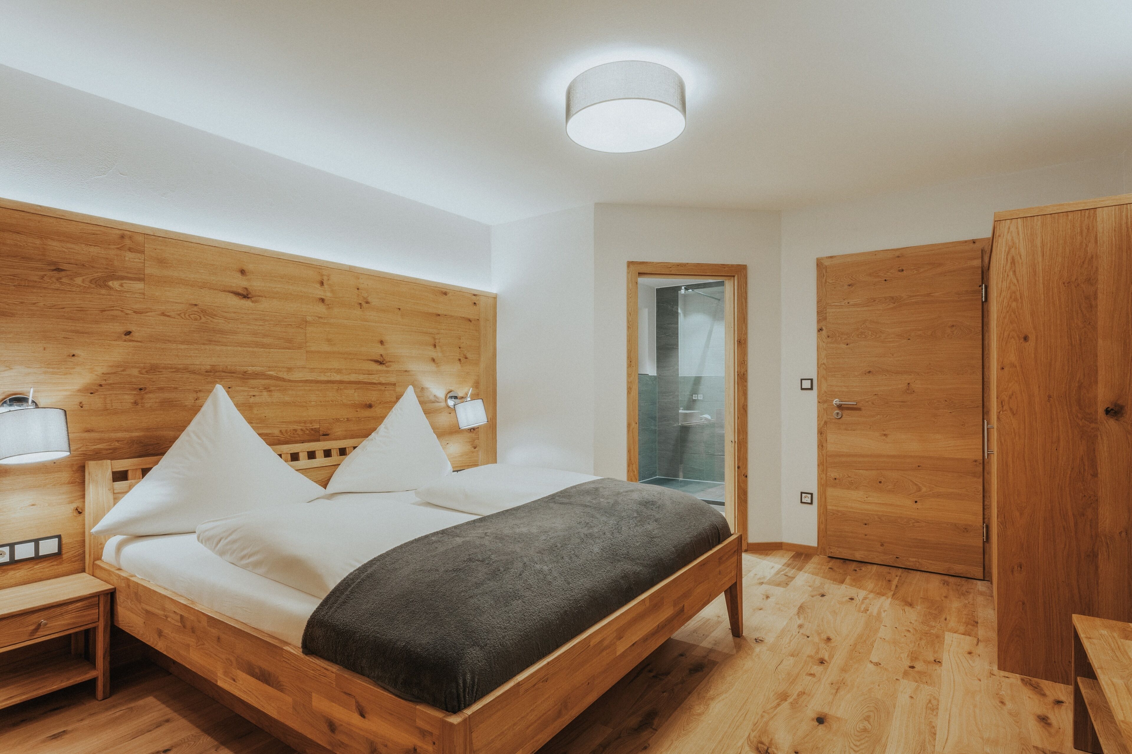 A modern bedroom with a wooden bed, bedside tables, and a wardrobe.