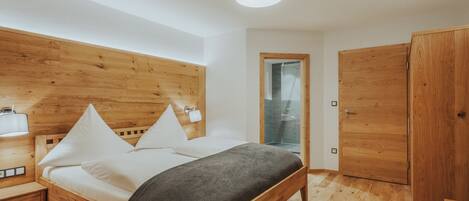 A modern bedroom with a wooden bed, bedside tables, and a wardrobe.