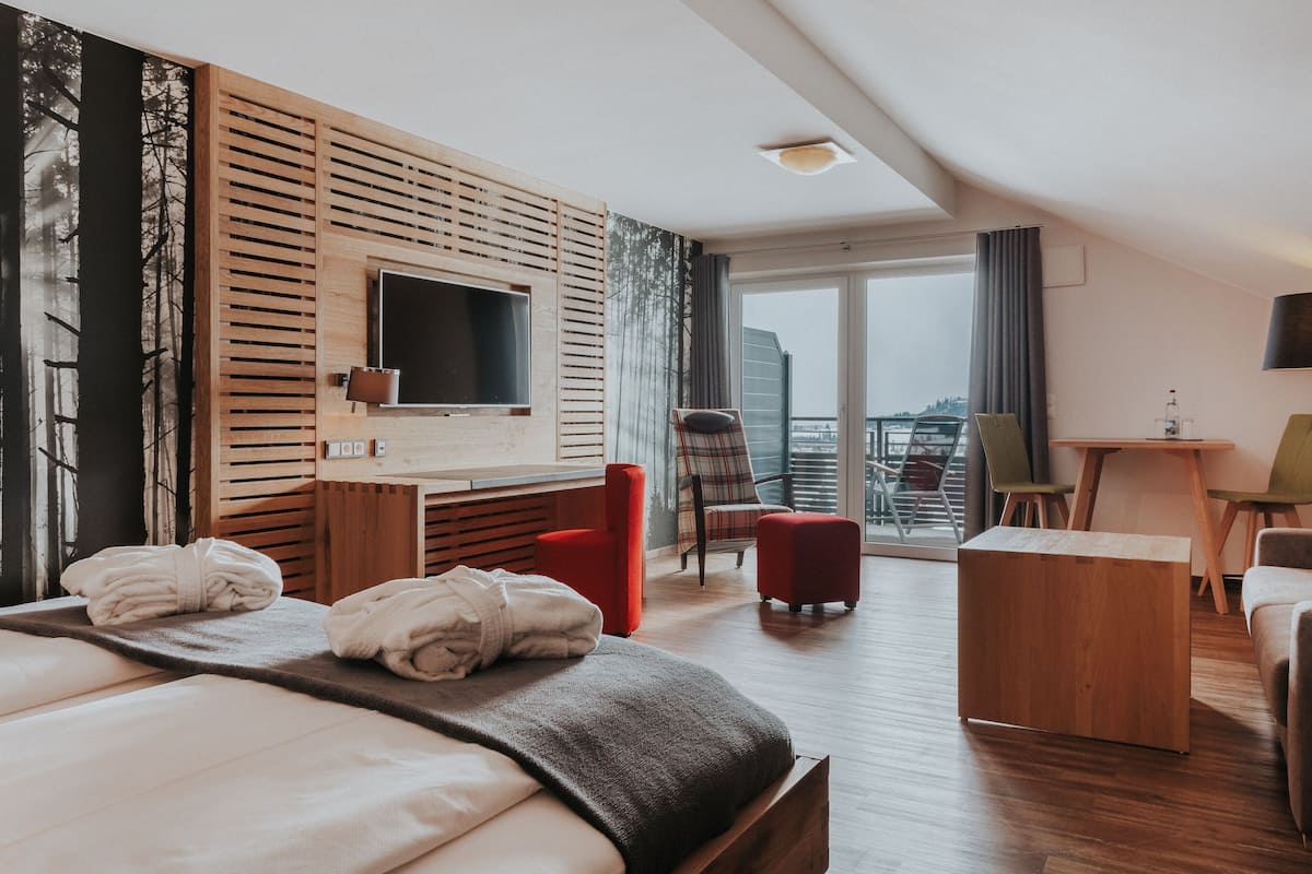 Een moderne hotelkamer met een groot bed, een televisie, een bureau en een balkon met uitzicht.