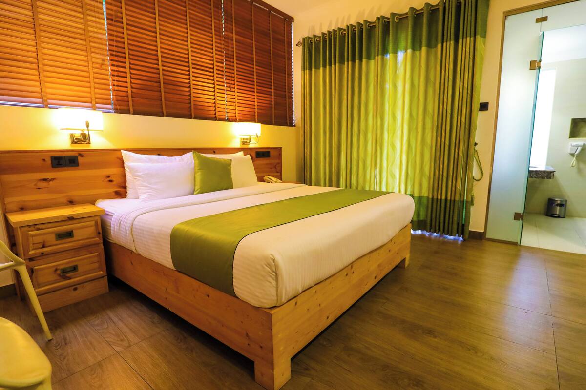 A wooden bed with a green and white bedspread, wooden headboard, and bedside tables with lamps.