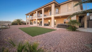 A multi-story house with a patio area, outdoor seating, and a view of the landscape.