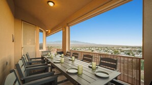 A dining area with a long table set for six, overlooking a scenic view of a desert landscape.