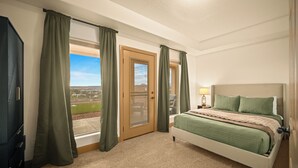 Une chambre avec un lit, une porte donnant sur un balcon et une vue sur l’extérieur.