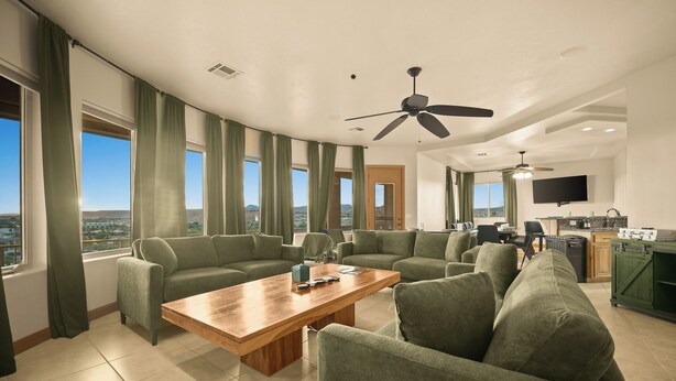 A spacious living room with a curved ceiling, large windows with curtains, a wooden coffee table, and a green sofa.