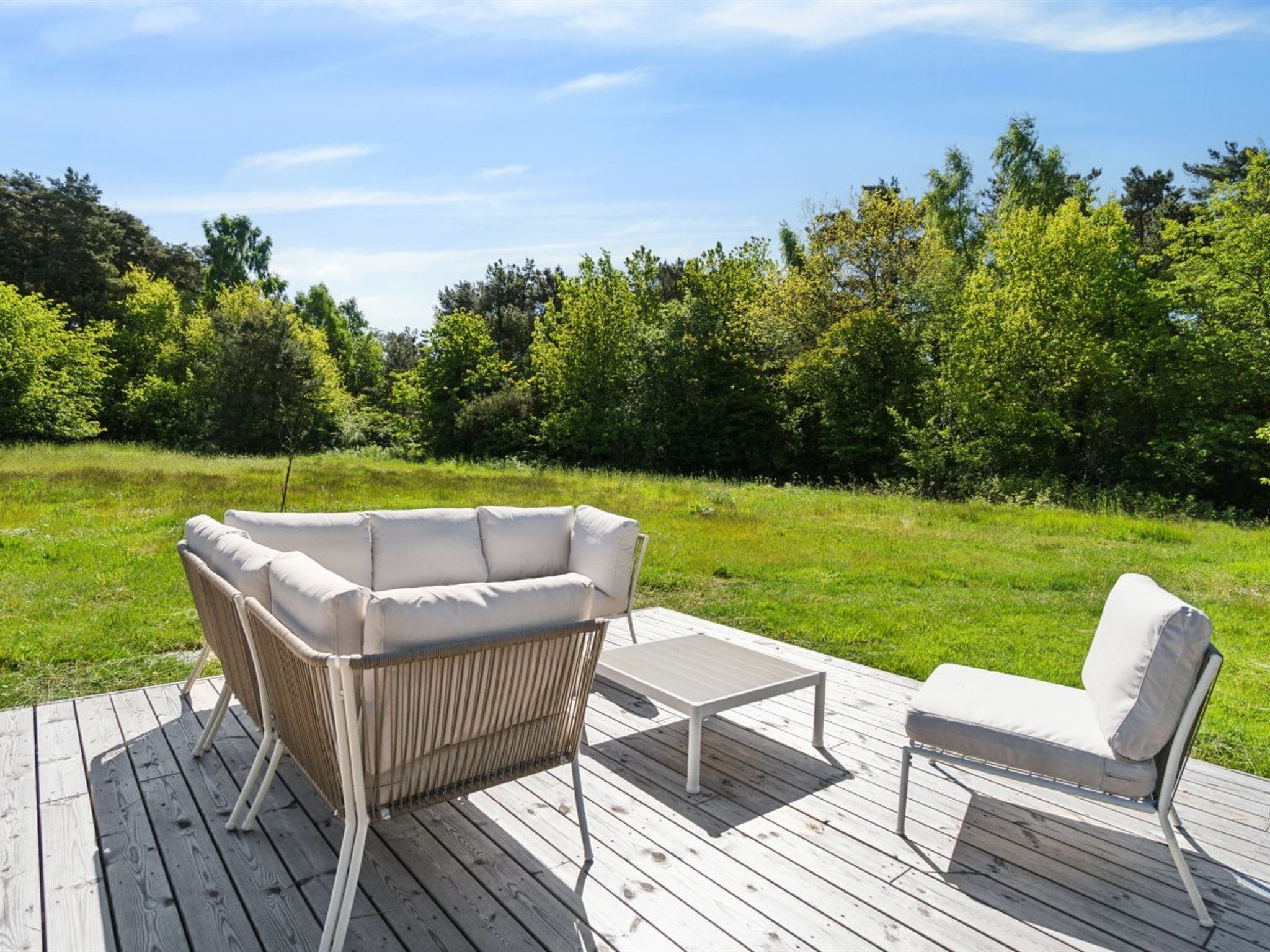 An outdoor deck with a wicker sofa, a small table, and a single chair.