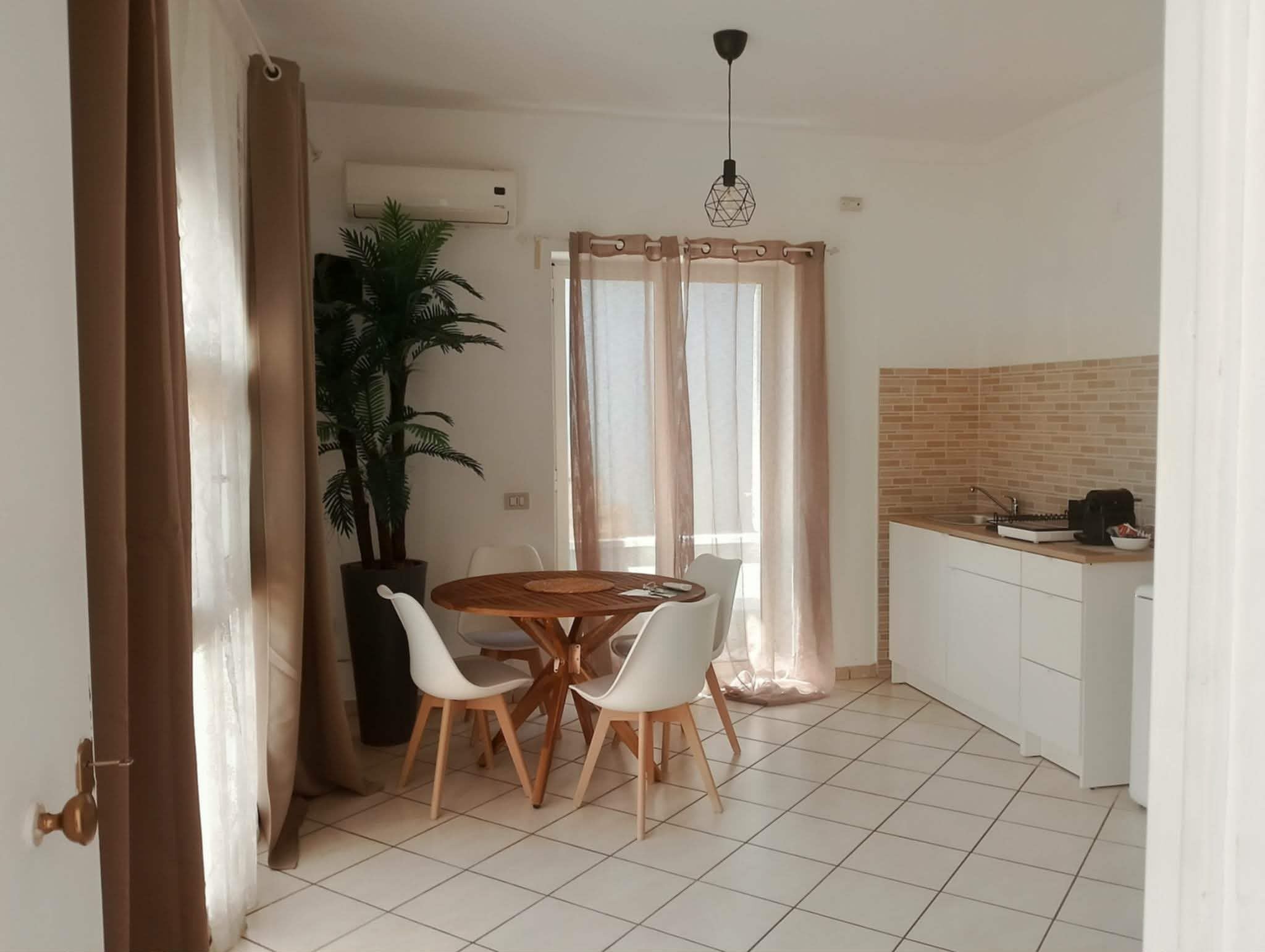 Une cuisine compacte avec un coin repas, une plante en pot et un sol carrelé.