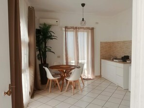 A compact kitchen with a dining area, a potted plant, and a tiled floor. - Dedalo (Pompei)