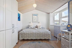 Une chambre à coucher avec un lit, un bureau, une fenêtre et un ventilateur de plafond.