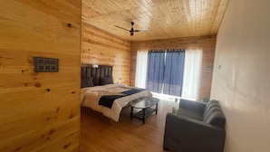Une pièce de cabane en bois comprenant un lit, une petite table, un canapé et un ventilateur de plafond.