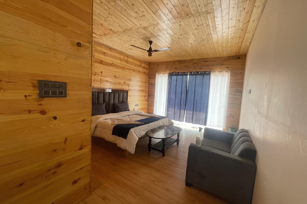 Una habitación de cabaña de madera con una cama, una mesita, un sofá y un ventilador de techo.