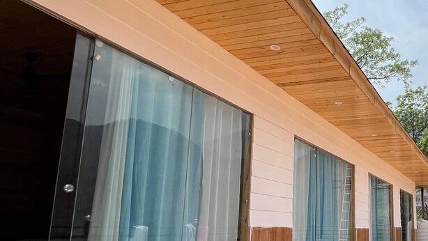 Un bâtiment moderne doté de grandes fenêtres et d’une terrasse en bois.