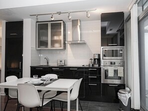 A modern kitchen with a dining area, featuring a built-in oven, microwave, and a coffee maker. - 1BR Condo w/ Balcony/Pool/Gym (Toronto)