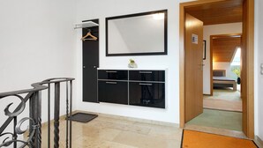 A hallway with a black cabinet, a mirror, and a wooden door leading to another room. - Apartment 'Morent' with Mountain View, Balcony and Wi-Fi (Achberg)
