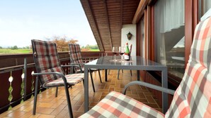 An outdoor patio with a table and chairs, a bottle of wine, and a view of the countryside. - Apartment 'Morent' with Mountain View, Balcony and Wi-Fi (Achberg)