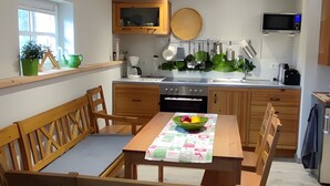 A modern kitchen with wooden cabinets, a dining table with chairs, and a built-in microwave. - Apartment 'Am Dächsberg' with Private Terrace and Wi-Fi (Plauen)