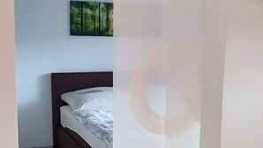 A bedroom with a bed, a painting on the wall, and a wooden floor. - Apartment 'Am Dächsberg' with Private Terrace and Wi-Fi (Plauen)