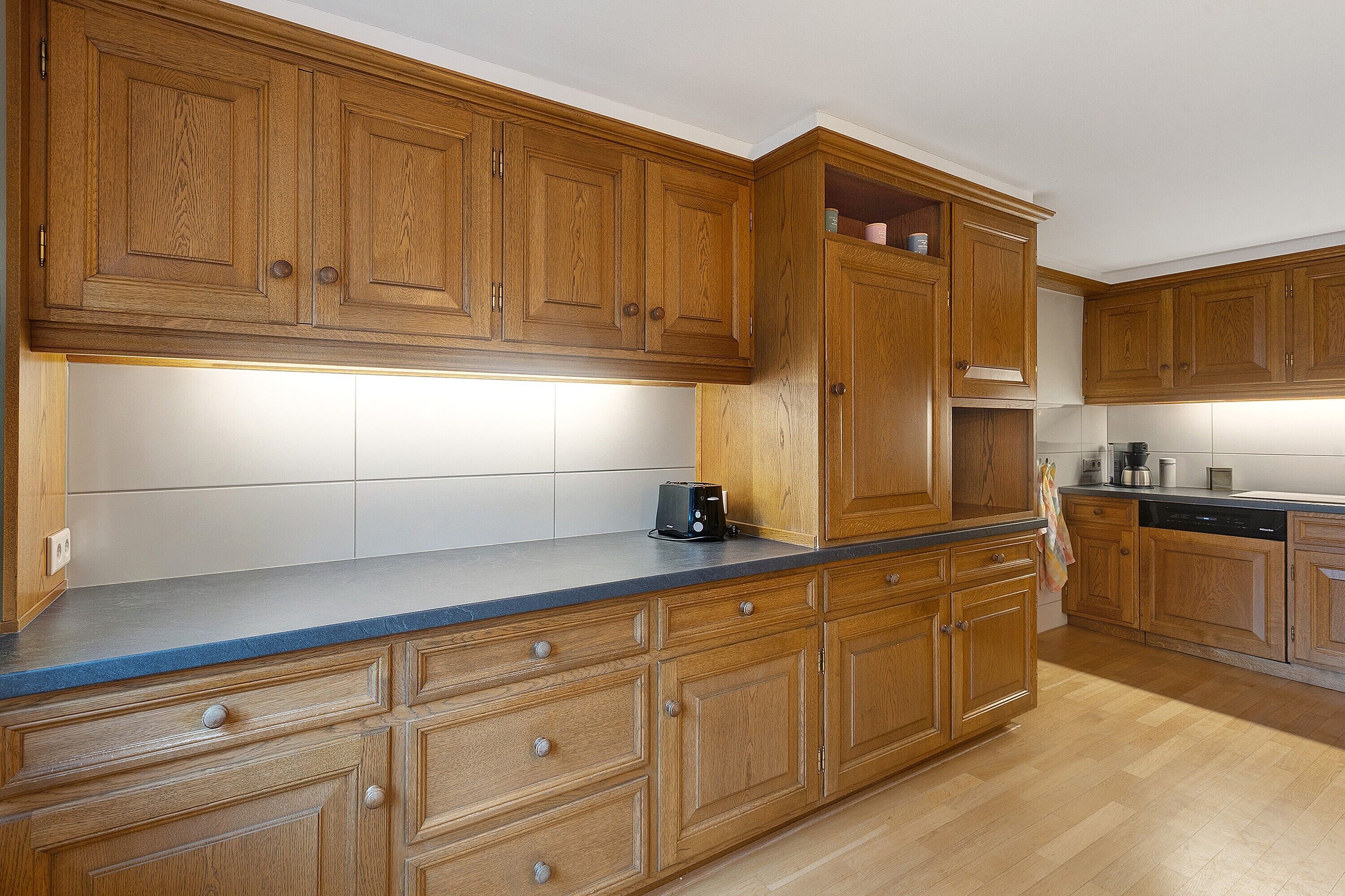 A kitchen with wooden cabinets, a blue countertop, and a dishwasher.