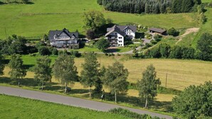 A rural landscape with a large house surrounded by green fields and trees. - Apartment 'Stötenberg' with Mountain View, Private Garden and Wi-Fi (Schmallenberg)