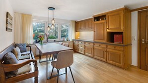 A modern kitchen with wooden cabinets, a dining table, and a bench. - Apartment 'Stötenberg' with Mountain View, Private Garden and Wi-Fi (Schmallenberg)