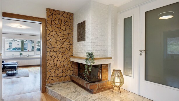 A modern interior with a fireplace, stone wall, and a view of the outside. - Apartment 'Stötenberg' with Mountain View, Private Garden and Wi-Fi (Schmallenberg)