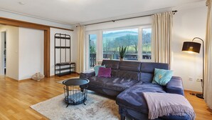 A modern living room with a sofa, a small table, and a view of the outdoors. - Apartment 'Stötenberg' with Mountain View, Private Garden and Wi-Fi (Schmallenberg)