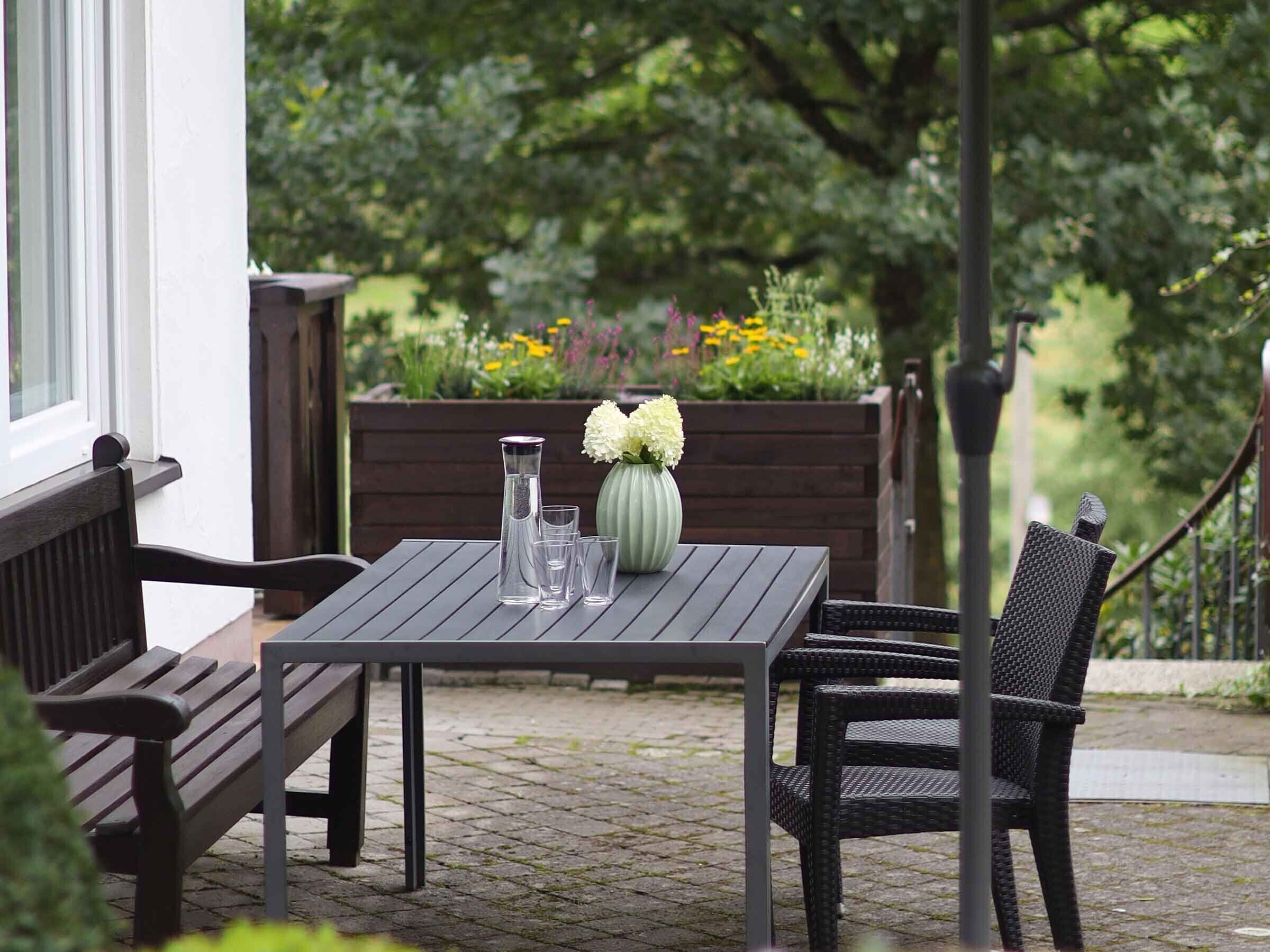 Eine Terrasse mit Tisch, Stühlen und einem Blumenstrauß.