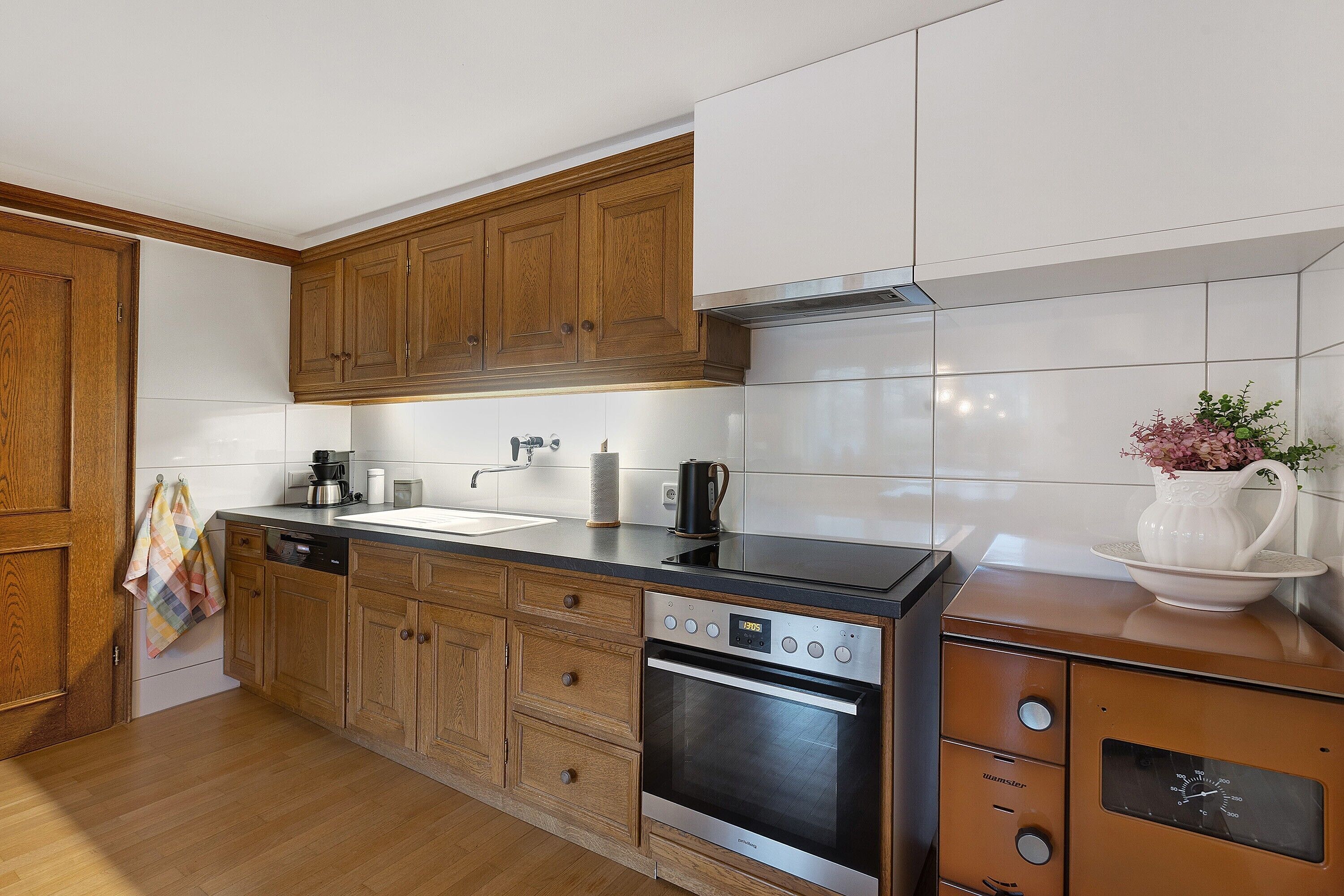 Una cocina con armarios de madera, horno de acero inoxidable, lavavajillas y cafetera.