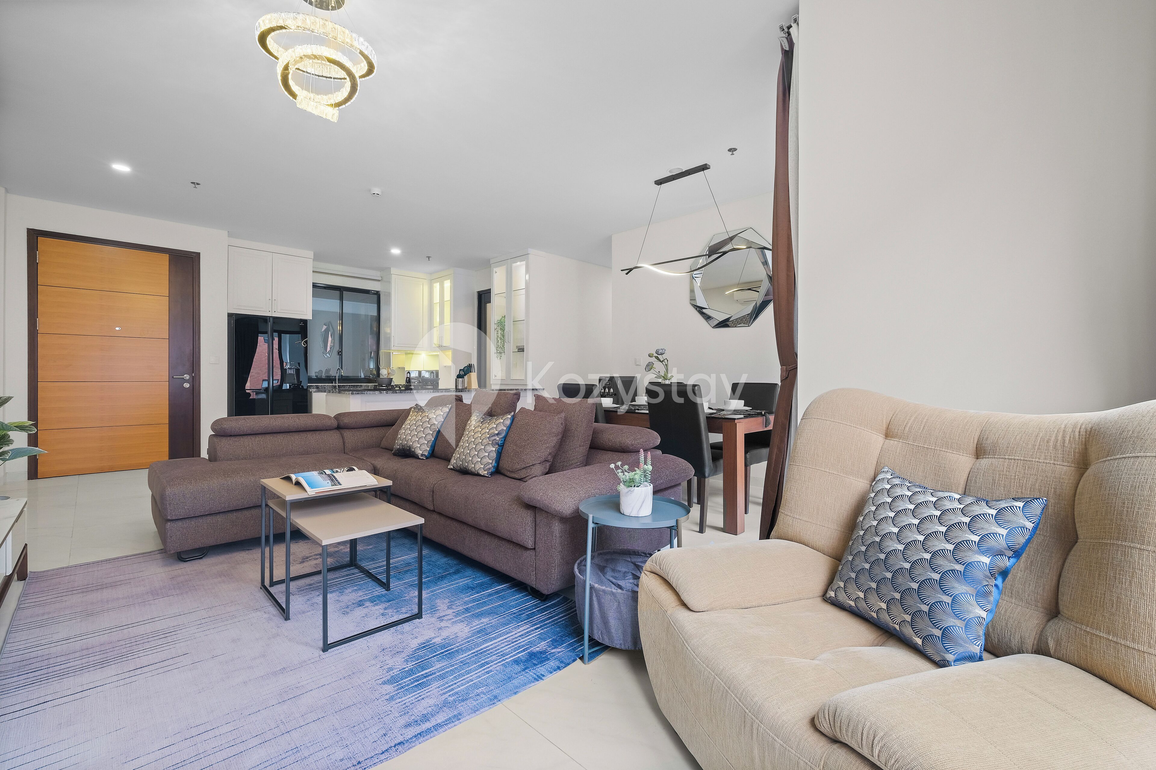 A modern living room with a sectional sofa, a coffee table, and a beige sofa.