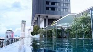 Un bâtiment moderne doté d’une piscine sur le toit et entouré de verdure.