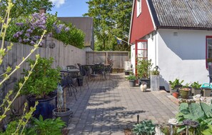 Un espace patio aménagé avec une table et des chaises, entouré de plantes en pot et d’une clôture en bois.