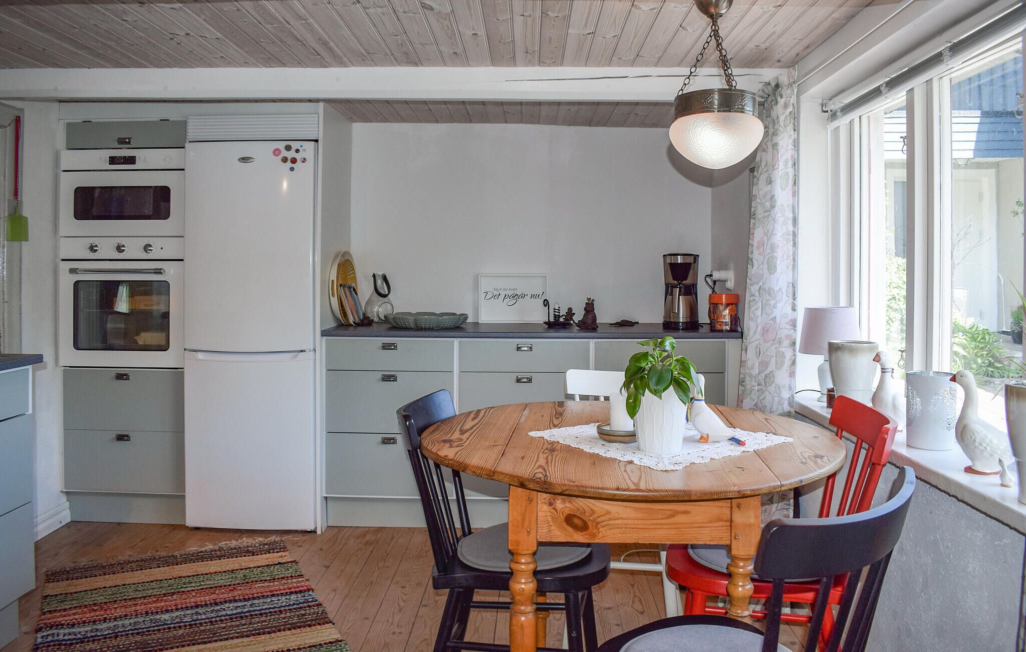 Une cuisine avec une table à manger en bois, des chaises et un réfrigérateur.