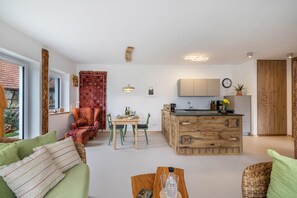 A modern living space with a sofa, a dining table, chairs, a kitchen area, and a wooden cabinet.