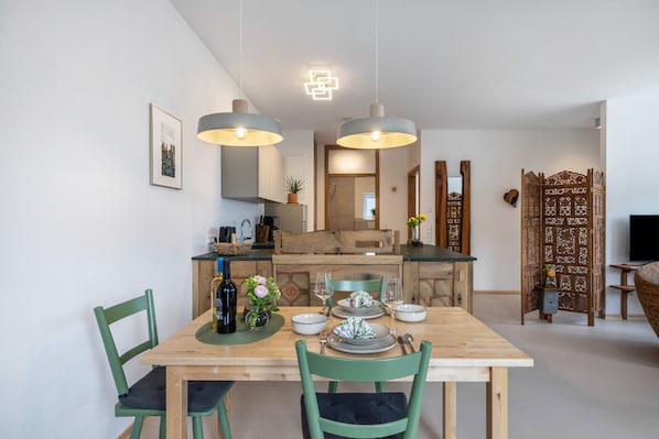 A dining area with a wooden table, chairs, and hanging pendant lights.