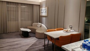 A modern hotel room with a sofa, dining table, and chairs, a coffee machine, and a water dispenser. - Powerlong Hotel Jinjiang (Quanzhou)