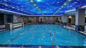 A large indoor swimming pool with clear lane dividers, surrounded by marble walls and a starry ceiling. - Powerlong Hotel Jinjiang (Quanzhou)