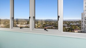 A room with three windows overlooking a cityscape. - Ambassador Beachfront Apartments (Burleigh Heads)