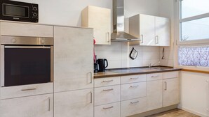 Et moderne køkken med rustfrie apparater, hvide skabe og et vindue med matteret glas.