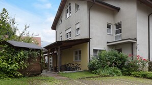 Een gebouw met twee verdiepingen, een overdekte veranda, een kleine tuin en fietsen die er buiten staan.
