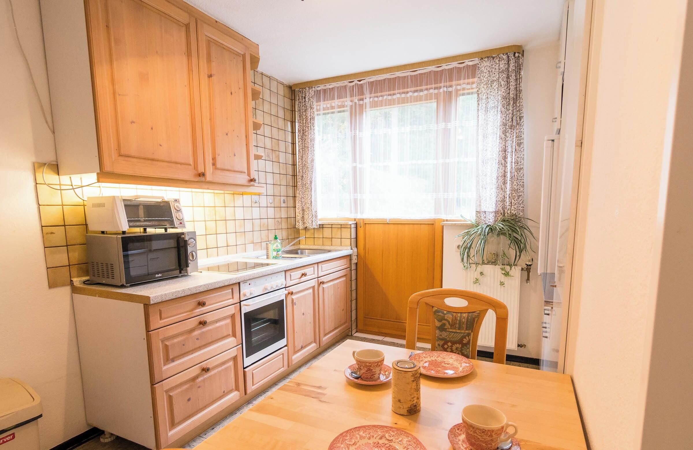 Une cuisine compacte dotée de meubles en bois, d’un four à micro-ondes, d’un évier et d’un coin repas avec une table et des chaises.