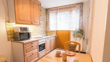 Une cuisine compacte dotée de meubles en bois, d’un four à micro-ondes, d’un évier et d’un coin repas avec une table et des chaises.