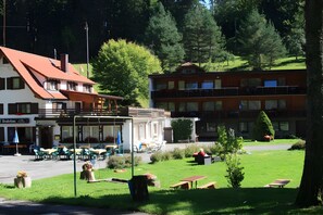 Un hotel con terraza al aire libre, un patio cubierto y vistas a una ladera boscosa.
