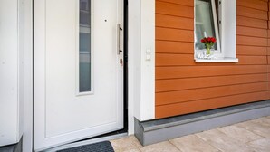 A white door with a small window, a welcome sign, and a wooden exterior. - Apartment 'Talblick' with Mountain View, Private Terrace and Wi-Fi (Loffenau)