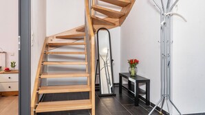 A modern staircase with wooden steps and metal railings, a mirror, a small table with a vase, and a coat rack. - Apartment 'Teufelsmühlblick' with Mountain View, Balcony and Wi-Fi (Loffenau)