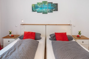 Une chambre avec un lit double doté d’une tête de lit en bois, deux tables de chevet ornées de petites plantes en pot et un tableau accroché au mur.