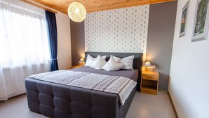 A bedroom with a large bed, bedside lamps, a wooden headboard, and a patterned wall.