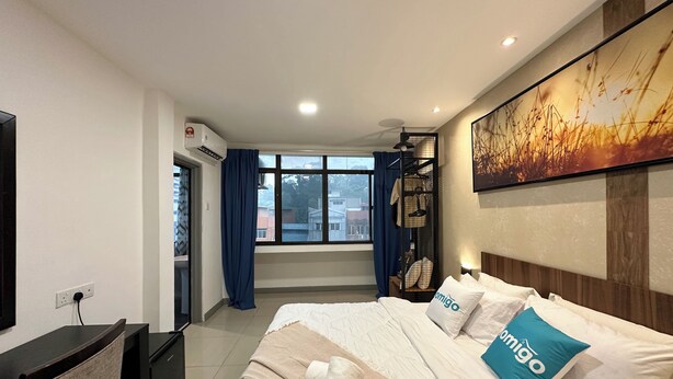 A hotel room with a bed, a desk, a chair, a TV, a window with curtains, and a painting on the wall. - Homigo - PWTC (Kuala Lumpur)
